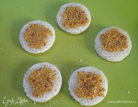 Из ломтиков хлеба/батона вырезать кружочки диаметром 3–4 см (или квадратики) и смазать их горчицей.