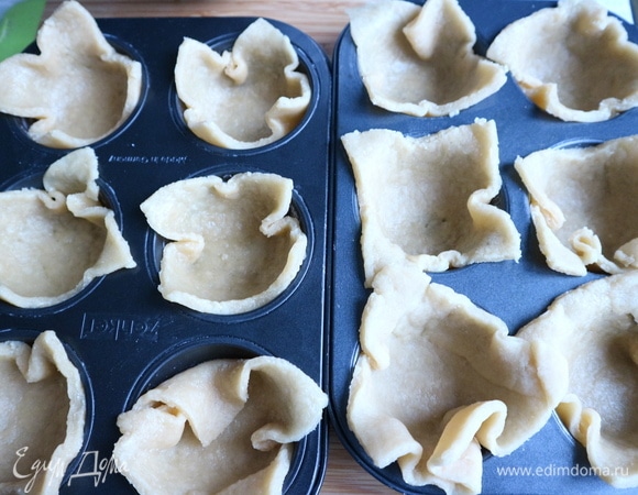 Формочки для капкейков смазать сливочным маслом, слегка посыпать мукой. Поместить в них кусочки теста таким образом, чтобы концы квадратов из теста выступали из формочек.