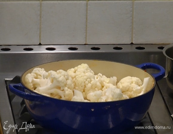 Разогреть в тяжелом сотейнике оливковое и сливочное масло и обжаривать куриные бедра по 3–4 минуты с каждой стороны, затем посыпать их нарезанным чесноком, перемешать и добавить в сотейник цветную капусту.