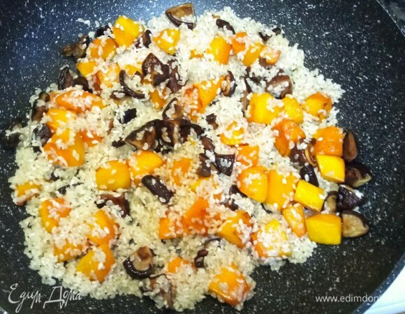 Добавляем чеснок и хорошо промытый в нескольких водах рис. Обжариваем 2 минуты, постоянно помешивая.