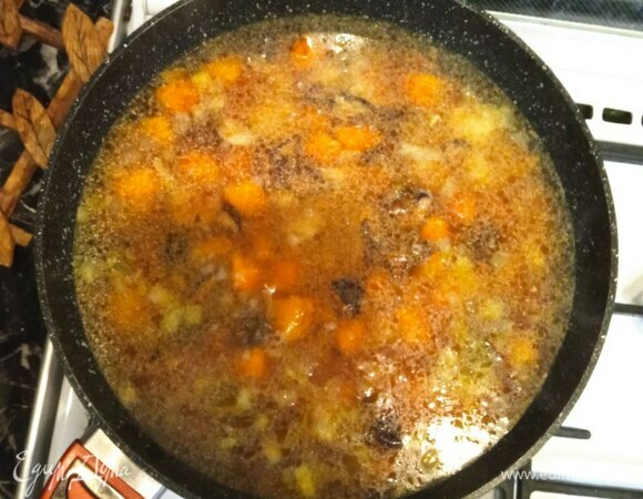 Разравниваем поверхность. Добавляем воду от грибов и простую воду так, чтобы она покрывала наши ингредиенты примерно на 1 см. Когда вода закипит, уменьшаем огонь, накрываем сковороду крышкой и готовим минут 30–40 до полного выпаривания жидкости.