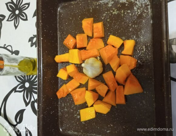 Тыкву очищаем, моем, обсушиваем бумажными полотенцами и режем средним кубиком. Выкладываем на противень, сбрызгиваем оливковым маслом. В середины кладем головку чеснока, которую тоже сбрызгиваем маслом. Ставим в предварительно разогретую духовку. У автора рецепта указано 400°C и 25 минут. В моей духовке максимум 300°C. У меня тыква провела в духовке минут 35–40.