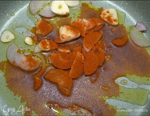 Разогреть в тяжелой сковороде оливковое масло, выложить лук и чеснок, посыпать паприкой и слегка обжарить.