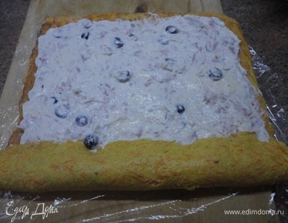 Смазать чуть теплый омлет творожной начинкой и свернуть рулет, помогая пищевой пленкой.