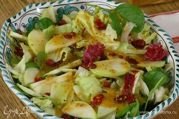 Салатные листья и нарезанные яблоки выложить в глубокую тарелку, посыпать клюквой, полить заправкой.