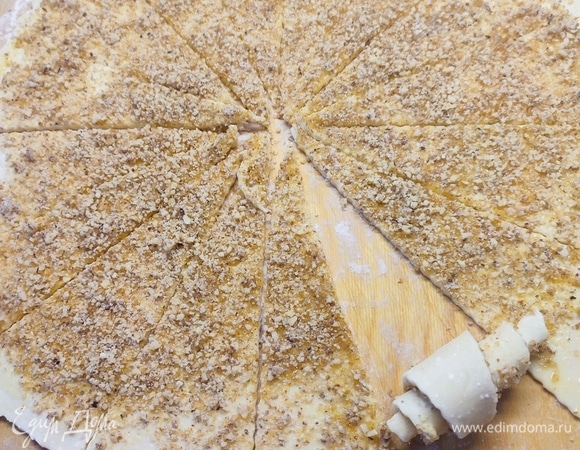 Тесто разделить на две части. Каждую раскатать в круг, смазать яйцом и посыпать начинкой. Разделить каждый круг на 16 частей и скатать их в рулетики.