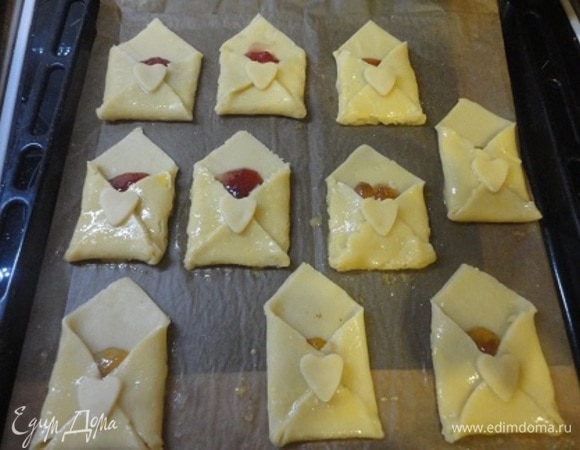 Из остатков теста вырезаем сердечки и помещаем в центр каждого конвертика. Из страха, что сердечки сползут, а ковертики расклеются, я решила скрепить их взбитым яйцом. Выпекаем печенье при температуре 180°С в течение 10–15 минут, до золотистого цвета. Не больше, иначе тесто будет сухим. В моей духовке понадобилось 15 минут.