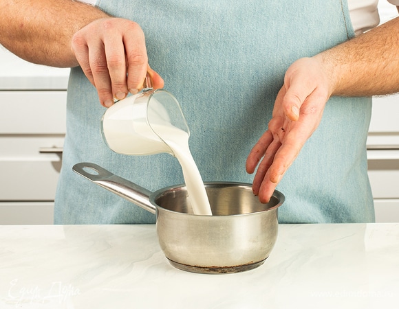 В это время подготовьте тягучий ганаш. Шоколад натрите на терке и соедините в сотейнике со сливками. Томите на медленном огне, аккуратно помешивая, пока крем не загустеет, около 5–7 минут.