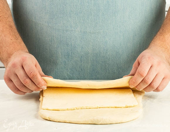 Посыпьте рабочую поверхность мукой, достаньте тесто и раскатайте его в пласт толщиной 5 мм. Положите в центр охлажденный маргарин «Пышка» и накройте его краями теста внахлест. Сложите тесто втрое и уберите в холодильник на 10 минут.