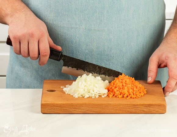 Мелко нарежьте лук и морковь. В сковороде с высокими бортами нагрейте растительное масло и обжарьте овощи до золотистого цвета.