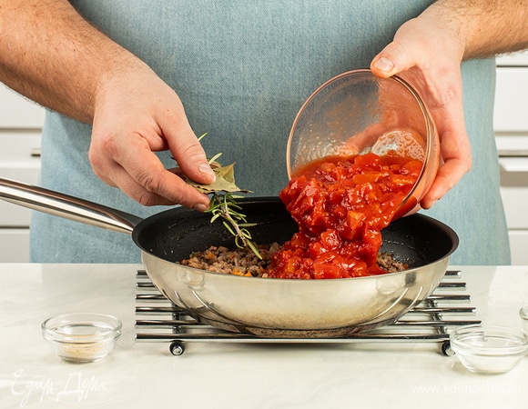 Добавьте протертые томаты, лавровый лист, сушеный чеснок и розмарин. Посолите и поперчите. Тушите соус под полуприкрытой крышкой в течение 40 минут. Затем удалите жесткую часть розмарина и лавровый лист.