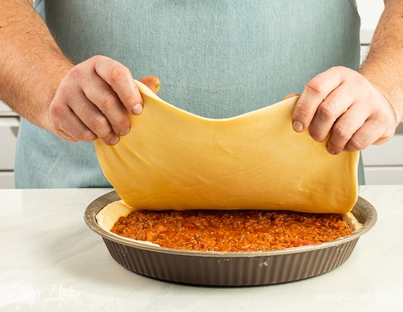 Раскатайте третью часть теста в пласт толщиной 3–5 мм. Накройте начинку этой заготовкой и хорошо скрепите края пирога.