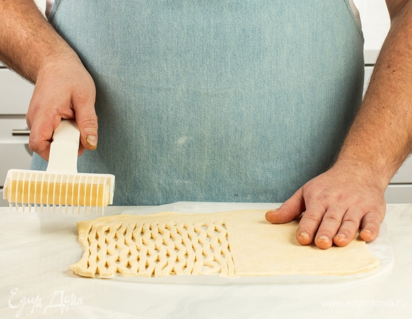 Достаньте из холодильника самую первую часть теста и сделайте на ней надрезы с помощью фигурного ролика.