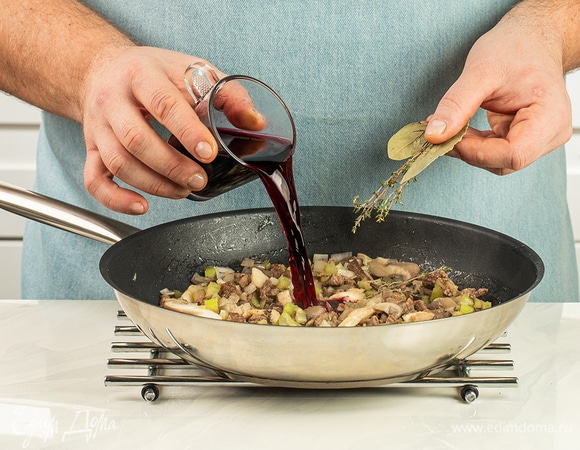 Влейте вино, посолите, поперчите, добавьте лавровый лист и тимьян. Убавьте огонь до минимума, накройте крышкой и тушите около часа или немного дольше.