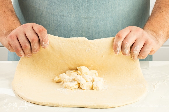 Подошедшее тесто раскатайте в прямоугольный пласт толщиной 1 см. По центру выложите комок из масляной крошки.