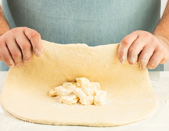 Подошедшее тесто раскатайте в прямоугольный пласт толщиной 1 см. По центру выложите комок из масляной крошки.