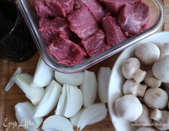 Мясо нарезать на куски средней величины. Шампиньоны почистить от земли, помыть, обсушить. Репчатый лук почистить, нарезать на крупные куски (сначала на половинки, затем каждую половинку на 3 части через центр). Проростки в центре луковиц удалить. Варено-копченый окорок (бекон) нарезать на кусочки.