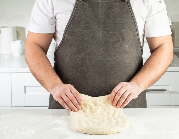 Посыпьте рабочую поверхность мукой и обомните тесто. Растяните заготовку в прямоугольный пласт толщиной 1,5–2 см.