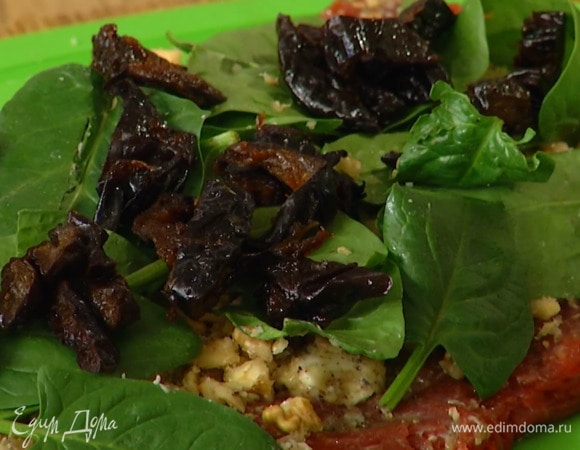 Смазать говядину по всему периметру пряным маслом, посыпать орехами, разложить шпинат и чернослив, затем переложить мясо на пищевую пленку и плотно свернуть в рулет.