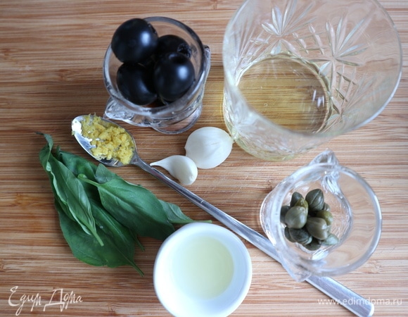 Духовку разогреть до 180°C. Почистить репчатый лук, чеснок. С лимона снять цедру на мелкой терке. Выдавить лимонный сок. Приготовить тапенаду. Смешать в ступке нарезанный чеснок, нарезанные маслины, базилик, цедру, каперсы, соль, перец, растолочь, добавляя лимонный сок. Добавить оливковое масло, перемешать. Посолить, поперчить.