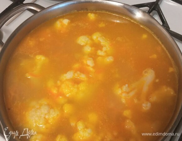 Режем картофель и отправляем его в кипящий бульон. Варим почти до готовности, закидываем цветную капусту и обжаренную морковь. Варим до готовности овощей, солим по вкусу.