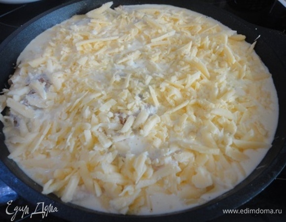 Наполненные блины выложить по спирали в круглую форму. Для заливки смешать сметану с яйцами, поперчить и залить блины. Посыпать тертым сыром и поставить в разогретую духовку.