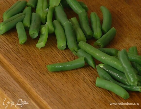Стручковую фасоль опустить на несколько минут в кипящую подсоленную воду, затем, слив воду, промыть ледяной водой и разрезать пополам.