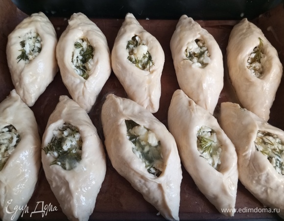 Переложить на противень. Взболтать яйцо, смазать пирожки, остатки яйца чайной ложкой влить в начинку.