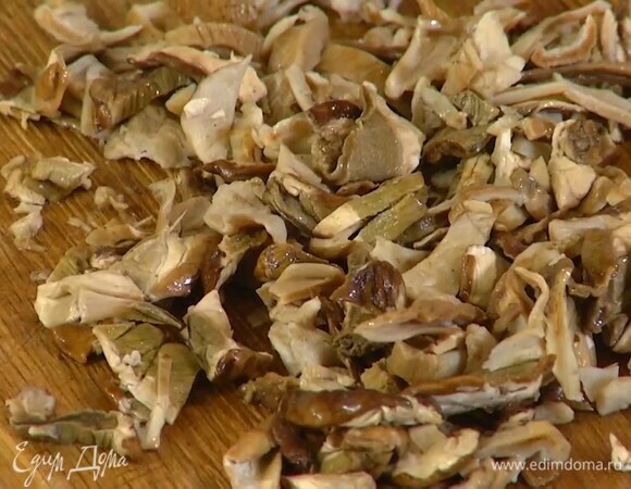 Белые грибы залить кипятком и дать постоять, затем жидкость процедить через сито в другую посуду, а грибы промыть горячей водой, промокнуть бумажным полотенцем и мелко порезать.