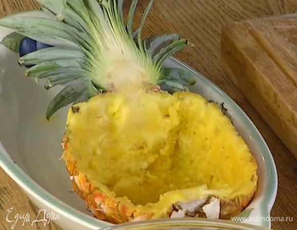 Ананас разрезать пополам вдоль вместе с зеленью и вырезать мякоть, не прорезая стенки, грубую сердцевину удалить.