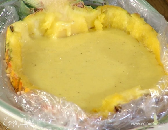 Стеклянную или керамическую форму выстелить двойным слоем пищевой пленки, поместить на нее половинку ананаса и наполнить сливочным кремом, затем накрыть пищевой пленкой так, чтобы она потно прилегала к поверхности крема, и отправить в холодильник на 4 часа.