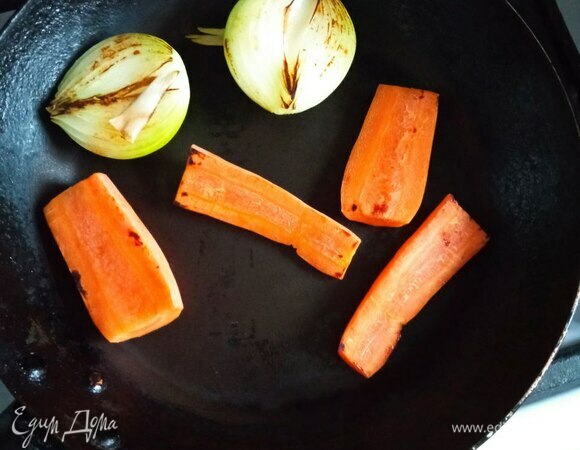 Сначала готовим бульон. Мясо промываем, заливаем холодной водой и ставим на огонь. Пока вода закипает, на разогретую сухую сковороду выкладываем разрезанную пополам луковицу срезом вниз, разрезанную пополам морковь и стебель сельдерея. Подрумяниваем со всех сторон на сильном огне.