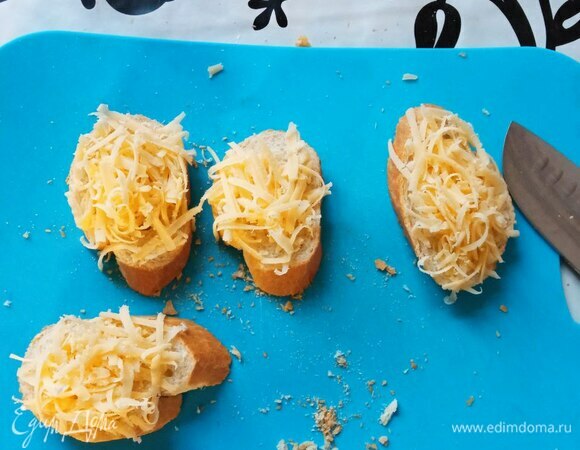 Багет нарезаем кусками средней толщины из расчета по два куска на порцию. Сыр трем на крупной терке. Сыр можно использовать любой плавящийся. Посыпаем багет сыром.