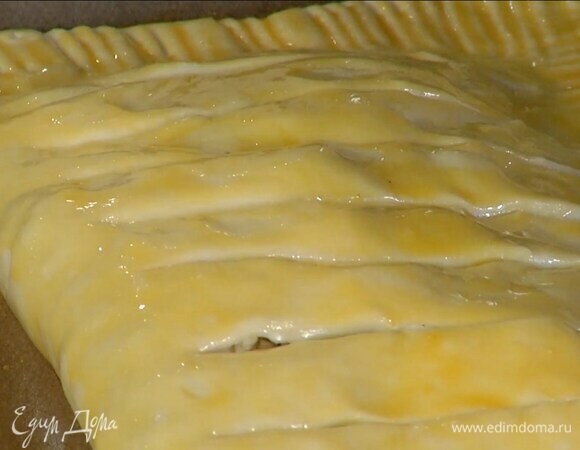 К желтку влить молоко, посолить, перемешать и смазать пирог, острым ножом сделать поперечные надрезы на верхней части теста, не прорезая края.