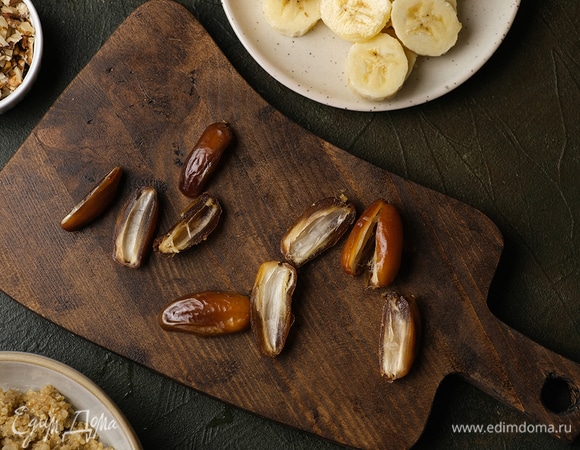 Киноа промойте, прокалите в сотейнике, залейте 100 мл воды и отварите до готовности. Банан нарежьте, грецкие орехи измельчите ножом, а у фиников удалите косточки.