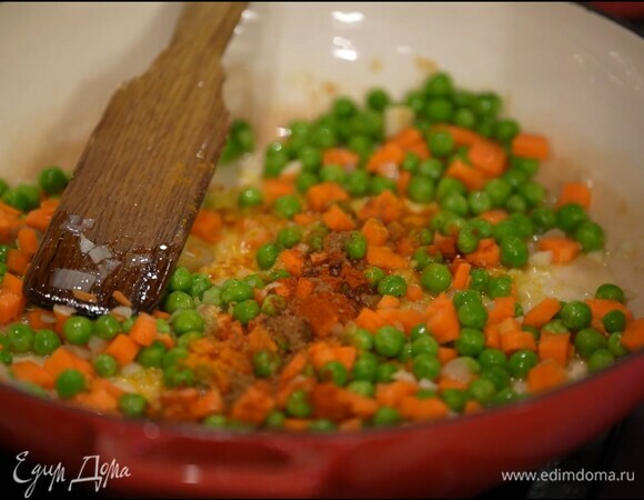 Морковь почистить, нарезать мелкими кубиками и отправить к луку с чесноком, добавить зеленый горошек, перемешать, всыпать куркуму, сладкую паприку, тмин, чили, посолить и еще раз перемешать.