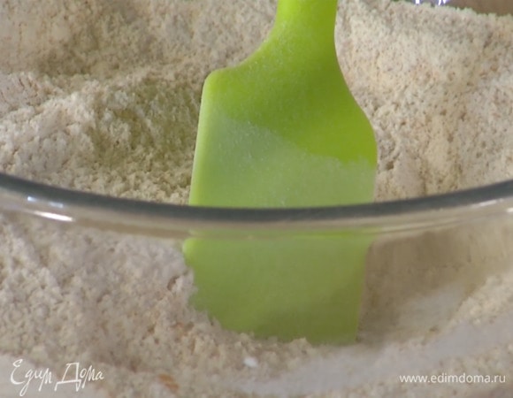 Порубить ножом 120 г пекана, так чтобы получились кусочки разного размера, и смешать в глубокой миске с мукой, изюмом и сахаром, добавить кокосовую стружку, корицу, разрыхлитель, соль и все перемешать.