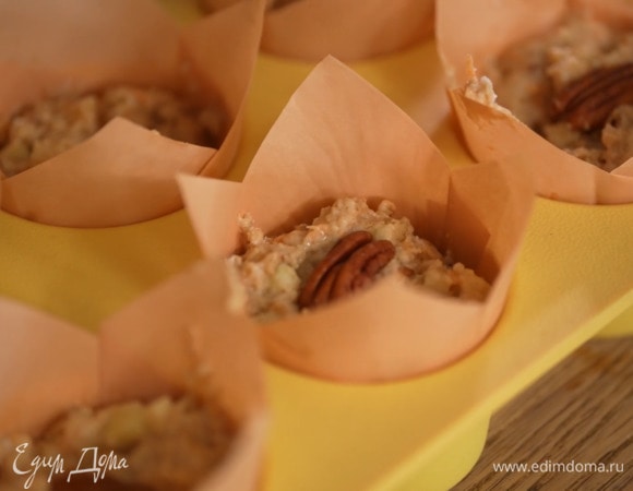 Разложить тесто в формочки с бумажными вкладышами, сверху украсить половинками пекана.