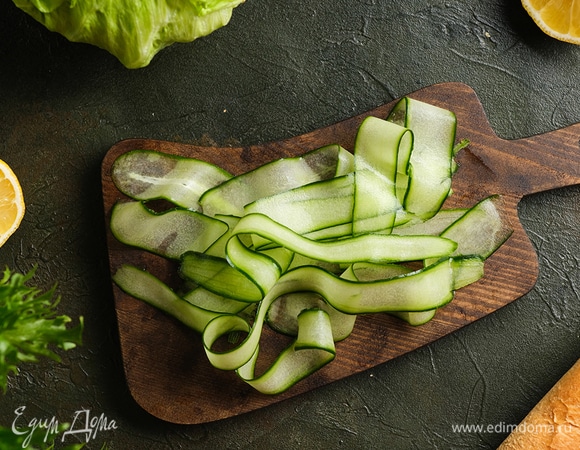 Очистите огурцы, с помощью овощечистки нарежьте их лентами.