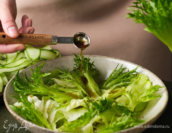 В салатник выложите листья айсберга и фриссе. Полейте частью заправки и перемешайте.