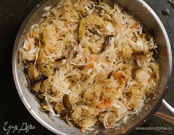Добавьте квашеную капусту, все перемешайте, накройте крышкой и тушите на маленьком огне до готовности.