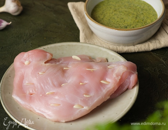 Оставшийся чеснок нарежьте полосками. Грудку индейки наколите ножом, вставьте в разрезы чеснок.