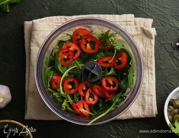 Приготовьте соус: кедровые орехи подсушите на сковороде без масла и выложите в чашу блендера, добавьте вяленые томаты, руколу, измельченный чеснок и перец чили.