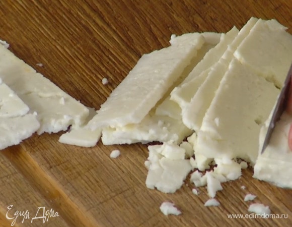 Фету нарезать тонкими хлопьями и выложить в салат.