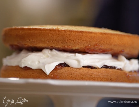 Остывший бисквит вынуть из формы и срезать тонким слоем запеченный верх. Нижние половинки коржей часто наколоть зубочисткой, полить пропиткой и смазать малиновым джемом, затем на один корж равномерно выложить взбитые сливки и накрыть вторым коржом малиновым слоем вниз.