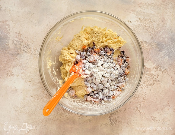 Слейте воду с сухофруктов, промокните плоды бумажным полотенцем и при необходимости нарежьте их. Добавьте к сухофруктам 2 ст. л. муки и перемешайте. Выложите сухофрукты в тесто и аккуратно перемешайте.