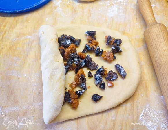 Тесто разделить на порции. Раскатать в пласт, посыпать сухофруктами и скатать в рулет. Потом скатать все в шар и положить в форму для выпекания.