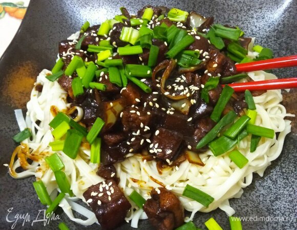 Сливаем лапшу, промываем холодной водой. Выкладываем лапшу. Сверху — соус из свинины и овощей. Украшаем зеленым луком и семенами кунжута. Можно добавить нарезанный соломкой свежий огурец. Традиционный корейский чаджанмен готов. Приятного аппетита!