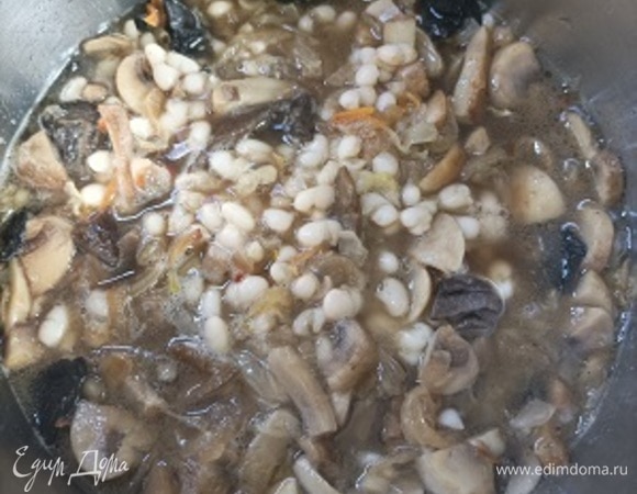 Залить грибным или фасолевым бульоном до уровня всех продуктов. Посолить по вкусу (если нужно, потому что капуста может быть соленой), хорошо вымешать и тушить на маленьком огне, пока уйдет практически вся жидкость, примерно 15–20 минут. Приправить свежемолотым черным перцем.