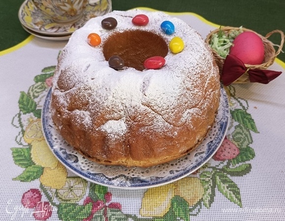 Разогреть духовку до 170°C и выпекать потицу 45–55 минут. Готовое изделие оставить в форме на 5 минут. Затем осторожно выложить на решетку или блюдо. Сразу смазать поверхность потицы сливочным маслом, щедро посыпать сахарной пудрой. Оставить остывать.